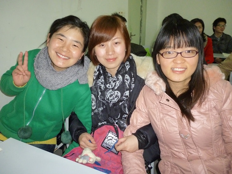 Three happy female Chinese university students linking arms.